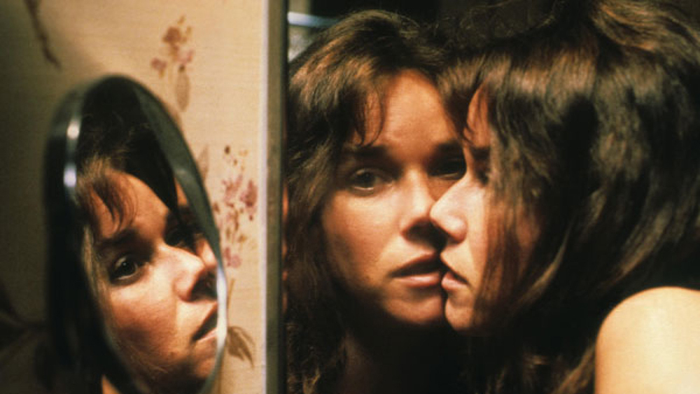 Barbara Hershey looks at herself in a mirror in the film The Entity